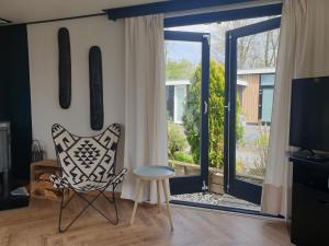 - un salon avec une chaise et une porte coulissante en verre dans l'établissement Vintage chalet Fereale II, à Grou