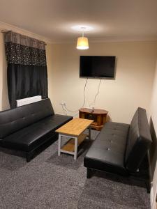a living room with a black couch and a table at Spacious 8 bed house in central Grimsby in Grimsby