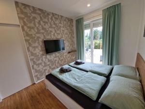 - une chambre avec un lit et une télévision murale dans l'établissement Platinum Bled, à Bled