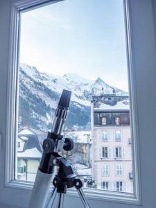un télescope devant une fenêtre avec une montagne dans l'établissement Appartement hyper centre 6 pers., à Chamonix-Mont-Blanc