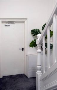 a white door with a plant next to a staircase at LFC Stadium Apartment 4 in Liverpool