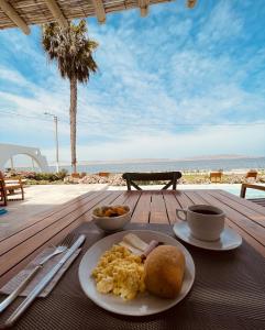 a plate of breakfast food on a table with the beach at Atoq Paracas Reserva in Paracas
