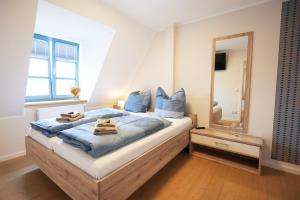 a bedroom with a bed with blue pillows and a mirror at Pension "Zum Reußischen Hof" in Thallwitz