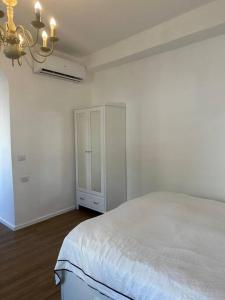 a white bedroom with a bed and a cabinet at Central Studio with a Garden in Tel Aviv