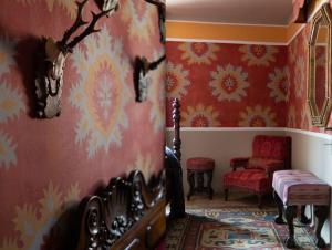 ein Wohnzimmer mit roten Wänden, einem Sofa und einem Stuhl in der Unterkunft Borgo Ferracina by BORGHI VENETI in Solagna