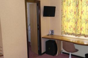 a room with a desk and a television on a wall at Hôtel Restaurant Des Lys in Le Coteau