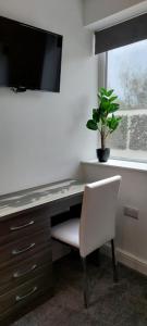 a desk with a white chair and a potted plant at The Chapel House in Saint Helens