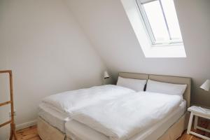 Schlafzimmer mit einem Bett mit weißer Bettwäsche und einem Fenster in der Unterkunft Wäscherei in Barkelsby