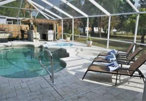 een zwembad met 2 stoelen en een patio bij Peachland getaway with pool and tiki bar in Port Charlotte