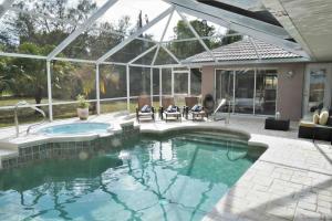 a swimming pool with two chairs and a house at Peachland getaway with heated pool and tiki bar in Port Charlotte