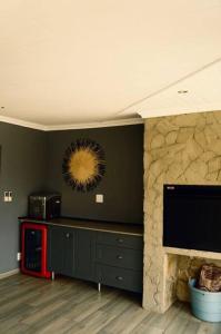 uma sala de estar com uma lareira de pedra e uma televisão em Dam'n Devine em Parys