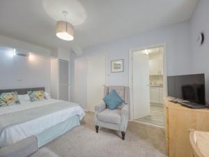 een slaapkamer met een bed, een stoel en een televisie bij Apartment 8 - Large Studio Sea Front-Ground floor -Free Parking in Paignton