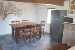 uma cozinha com uma mesa com cadeiras e um frigorífico em Gîte de l'arbre perché à Langel em Armissan