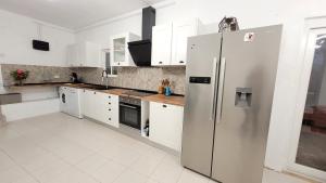 a kitchen with white cabinets and a stainless steel refrigerator at La Casa d'Olhão in Quelfes