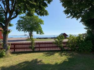 a fence with a tree and a house in the background at Mast Hav B&B in Bergkvara