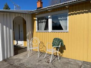 une maison jaune avec deux chaises et une fenêtre dans l'établissement Berget, à Charlottenberg