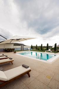 a swimming pool with an umbrella and lounge chairs at Smaris Collection luxury villas. ''Villa Stella''(Sea side villa) in Sisi