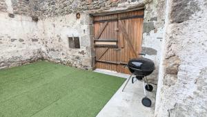 einen Grill in der Ecke eines Gebäudes mit einer Tür in der Unterkunft Le Puy de Côme in Saint-Diéry
