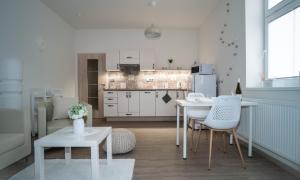 a kitchen with white tables and chairs in a room at Apartmánový dům Sklípek in Trutnov