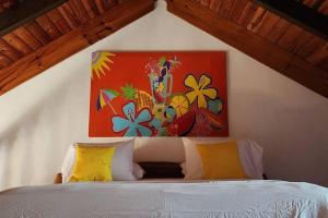 Appartements au cœur de Maharepa في Maharepa: غرفة نوم بسرير مع لوحة على الحائط