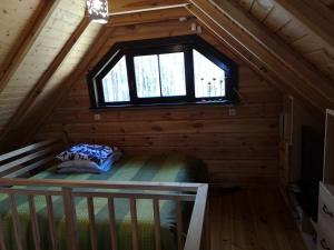 a bedroom in a log cabin with a window at Antalieptės sodyba in Baibiai