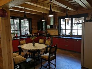 a kitchen with a table with chairs and red cabinets at Antalieptės sodyba in Baibiai