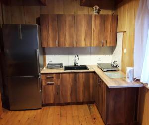 a kitchen with wooden cabinets and a stainless steel refrigerator at Zakątek nad Sanem in Załuż