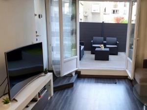 a living room with a television and a patio at Superbe appartement avec jardin proche Versailles in Saint-Cyr-lʼÉcole