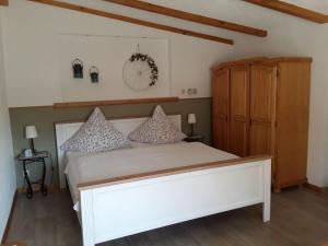 a bedroom with a white bed and a wooden cabinet at Ferienhaus in Zempin mit Garten in Zempin