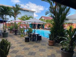 a resort pool with tables and chairs and palm trees at Hotel Babylon in Paramaribo