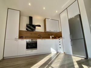 a kitchen with white cabinets and a stainless steel refrigerator at Chata North Point Zuberec pod Roháčmi in Zuberec