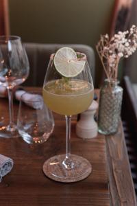 a wine glass with a lime slice in it on a table at Hôtel Maison Doron in Beaufort