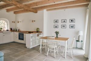 a kitchen with white cabinets and a table and chairs at Gemütliches Ferienhaus - Kornlager in Barkelsby