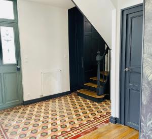 un couloir avec une porte noire et un escalier avec un étage dans l'établissement Jolie m'Home*Le Puy du Fou, à Mauléon