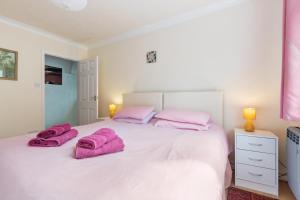 una camera da letto con un letto bianco e asciugamani rosa di Temple Bar Apartment - Sea Front Views ad Amroth