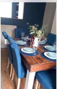 a wooden table with blue chairs and a blue dining room at Sea views Family & Relocators by O & J Properties in Shoreham-by-Sea