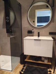 ein Badezimmer mit einem weißen Waschbecken und einem Spiegel in der Unterkunft Odenwald-Lodge mit Infrarotsauna und E-Ladestation "Haus Purpur" in Reichelsheim