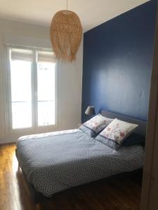 - une chambre dotée d'un mur bleu et d'un lit avec des oreillers dans l'établissement L'Aiguillon, bel appartement hyper-centre, à Brest