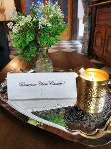 uma mesa com um cartão, uma vela e flores em Le gîte du Brouage em Chauny
