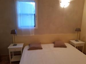 een slaapkamer met een wit bed, 2 tafels en een raam bij Vacances en Camargue proche de la mer climatisé in Aigues-Mortes