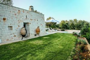 een stenen gebouw met twee vazen in de tuin bij Tenuta Lamia degli Ulivi - Ostuni Puglia - Ancient Lamia and Modern Villa in Ostuni
