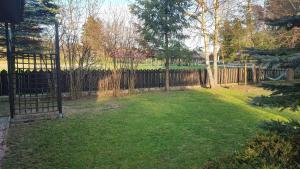 a backyard with a fence and a yard with green grass at Komfortowy dom nad jeziorem Mielno, Mazury in Mielno