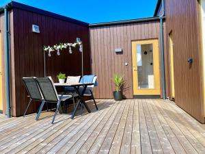 a patio with a table and chairs on a deck at Fresh hytte ved Borestranden med to soverom og hems in Klepp
