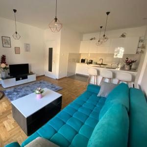 a living room with a blue couch and a kitchen at Harmony Suite in Trebinje