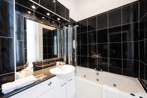 a black tiled bathroom with a sink and a bath tub at Kildonan Lodge Hotel in Edinburgh