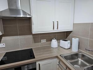 a kitchen with white cabinets and a sink at 1 bed modern flat in Didcot