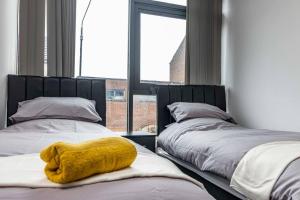 a bedroom with two beds with a yellow towel at Modern flat in Eastwood Town centre in Eastwood +2 photos