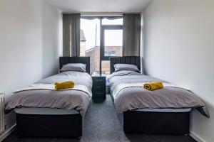 two twin beds in a room with a window at Modern flat in Eastwood Town centre in Eastwood