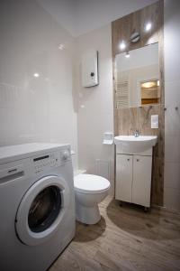 a bathroom with a washing machine and a sink at Apartamenty Kopernika in Toruń