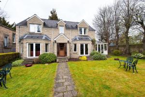 una casa con un cortile con sedie e un prato di Kildonan Lodge Hotel a Edimburgo